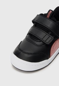 Svart syntetisk lær sneakers med borrelås, med en teksturert rosa detalj og en hvit gummisåle.