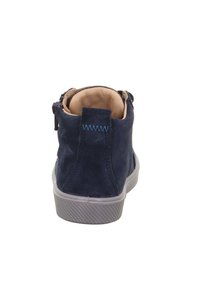 Granatowe zamszowe sneakersy widziane z tyłu, z brązowym wyściełanym kołnierzem i szarym gumowym podeszwa.