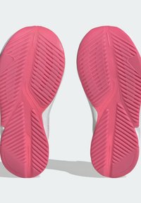 Scarpe sportive con suola in gomma rosa con battistrada a motivo, parte superiore bianca con dettagli colorati e una texture liscia su tutta la superficie.