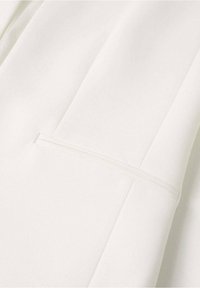 White fabric with a smooth texture and subtle sheen. Features a vertical seam and a discreet pocket detail.