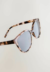 Lunettes de soleil à motif écaille de tortue avec un design œil de chat prononcé. Verres gris, monture épaisse et branches effilées.