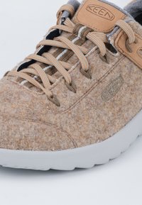 Braune Filz-Sneaker mit grauen Stoffakzenten, orangefarbenen und beigen Schnürsenkeln sowie einer weißen Gummisohle. Verfügt über ein Logopatch und eine strukturierte Oberfläche.