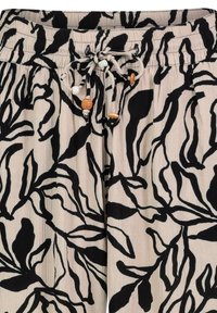 Black and beige floral patterned pants with an elastic waistband and drawstring, featuring wooden and white bead accents. Textured fabric.