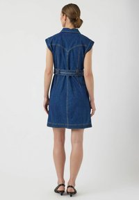 Denimkjole med kort erme, belte i midjen og detalj med bakstykke. Mørkeblå stoff, kne-lengde, ferdig med kontrastsøm.