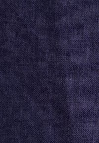 Tessuto blu navy testurizzato con un motivo tessuto, che presenta una finitura ruvida e opaca. Senza motivi o decorazioni visibili.