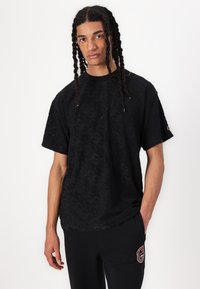 Tricou scurt negru cu un model geometric texturat. Croială lejeră, decolteu rotund, realizat dintr-un material moale. Poartă-l cu pantaloni negri.