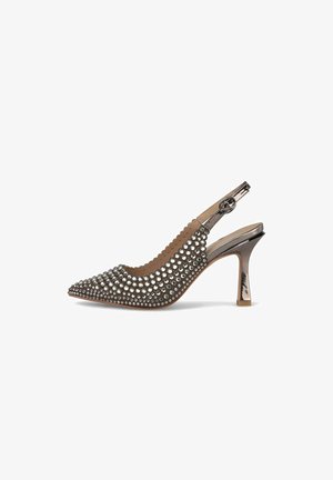 Talons slingbacks à bout pointu en beige avec des accents métalliques et ornés de clous ronds. Dotés d'un bord festonné et d'un talon élancé.