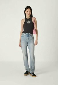 Top negru fără mâneci cu un design floral, blugi bleu deschis, geantă roz și teniși negri cu talpă din cauciuc. Îmbrăcăminte simplă și casual.