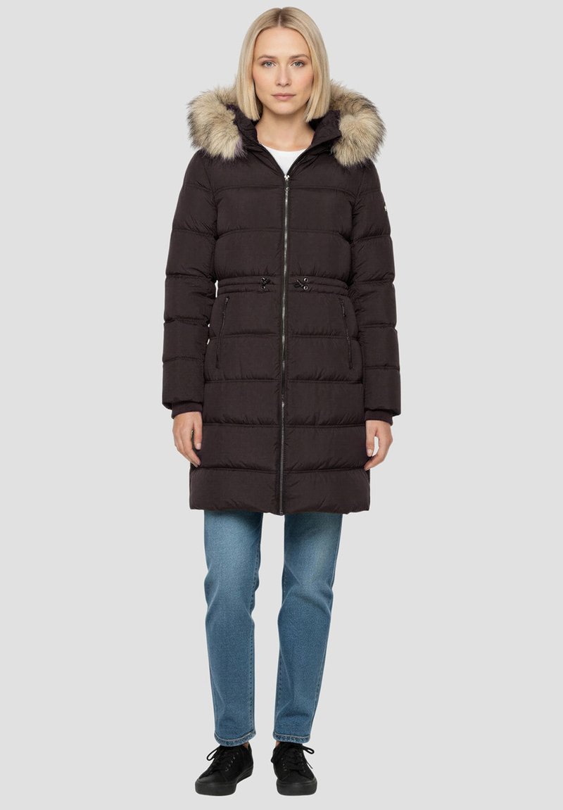 Zwarte donsjas met een capuchon met bontvoering, horizontale doorgestikte structuur, ritssluiting aan de voorkant, getailleerde taille en zijzakken. Gecombineerd met een blauwe spijkerbroek.