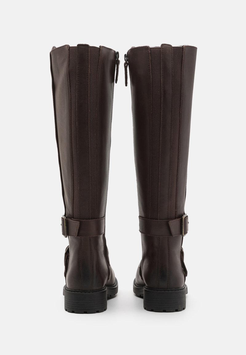 Brązowe skórzane buty za kolano o smukłym designie, z pionowymi szwami, bocznym zamkiem błyskawicznym i regulowanymi paskami na kostce.
