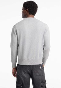 Suéter gris de punto con cuello redondo, puños y dobladillo acanalados. Textura suave, silueta ajustada y costuras mínimas en la parte posterior.