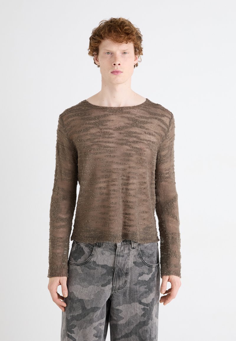 Brun tekstureret langærmet skjorte med vandrette striber, parret med grå camouflerede jeans med en afslappet pasform og lommer.