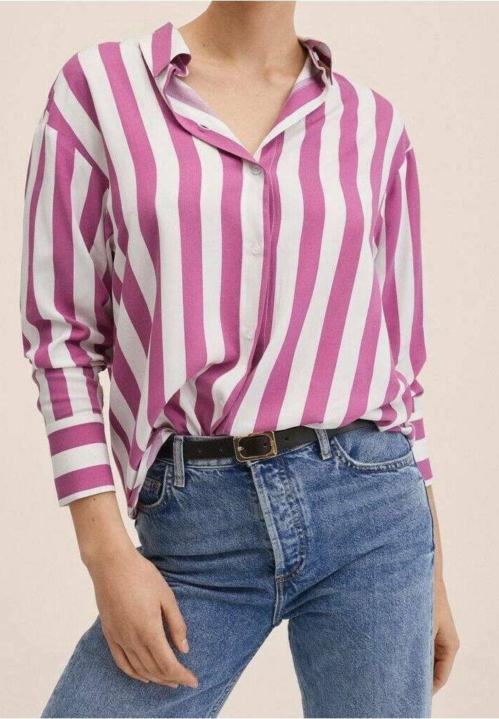 Personne portant une chemise à rayures verticales roses et blanches rentrée dans un jean bleu avec une ceinture noire.