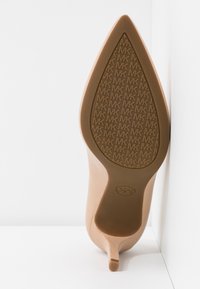 Semelle d'une chaussure à talon aigu beige avec un motif texturé du logo MK pour l'adhérence et un talon fin.