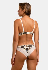 Ensemble de bikini avec imprimé floral en crème, featuring des finitions en dentelle. Le haut a des bretelles ajustables ; le bas offre une couverture modérée.