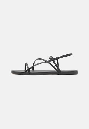 Black flat sandals feature thin straps, a simple design, and a minimalistic sole, offering a sleek, open-toe silhouette.