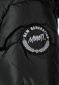 Black puffer jacket featuring a circular embroidered patch with "NEW GENERATION" and "MMOTTI." Accompanied by white laurel accents.
