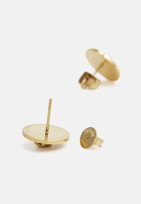 Gold stud earrings featuring a circular design with a polished finish and etched logo detail on the surface. Includes back clasp.