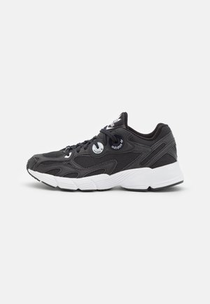 Black athletic shoe featuring a breathable mesh upper, thick white sole, and silver accents, with a contoured design and lacing system.
