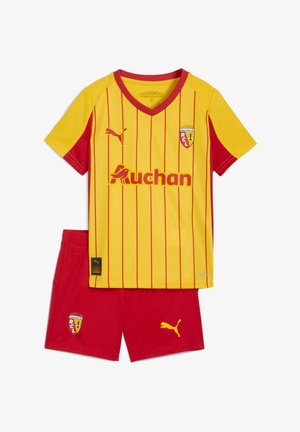 Maillot de football à rayures jaunes et rouges avec le logo Auchan, l'écusson du RCL, et un short rouge assorti avec le logo Puma et l'écusson du RCL.