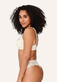 Reggiseno color crema con motivo in pizzo, con coppe morbide, spalline regolabili e mutandine abbinate con rifiniture in pizzo, caratterizzati da trame delicate e design senza cuciture.