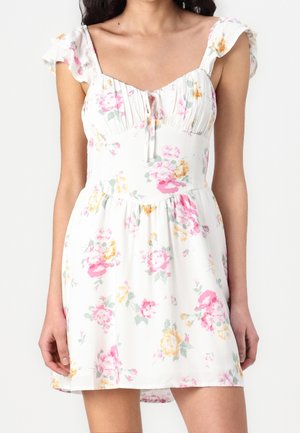 Biała sukienka bez rękawów z różowo-żółtym kwiatowym wzorem, falbaniaste ramiączka, marszczony biust i wiązanie w talii.