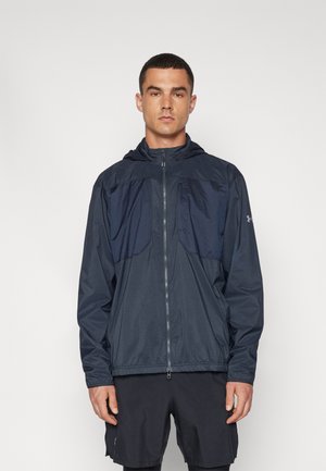 Veste coupe-vent marine avec fermeture éclair et capuche. Dotée d'un panneau supérieur texturé et de poignets élastiques, fabriquée en matériau léger et résistant à l'eau.