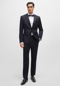 Man In Calvin Klein Black Satin Edged Notch Lapel Tuxedo BOSS Suit