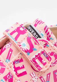 Rosa canvas-sko med färgstarkt tryckt mönster, med blå och vita detaljer. Kardborreband och svart logotypetikett på sidan.