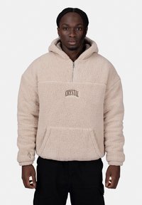 Beige fleece pullover with a hood, half-zip, front pocket, and "CRYSTAL" embroidery. Textured, soft fabric with ribbed cuffs.