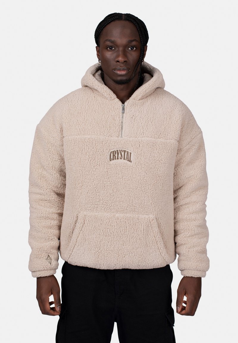 Beige fleece pullover with a hood, half-zip, front pocket, and "CRYSTAL" embroidery. Textured, soft fabric with ribbed cuffs.