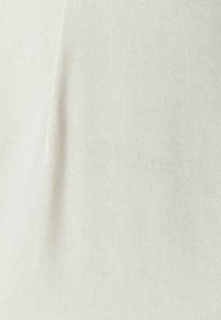 Jasno beżowa tkanina z teksturowanym splotem. Powierzchnia wydaje się miękka i nieco nierówna, odpowiednia do tapicerki lub odzieży.