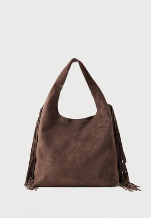 Καφέ σουέτ τσάντα ώμου με φαρδιά τιράντα και μακριές φούντες και στις δύο πλευρές, παρουσιάζεται πάνω σε απλό φωτεινό φόντο.