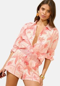 Light pink shirt with a deep V-neck and loose sleeves, featuring a coral marine pattern; paired with matching smocked shorts.