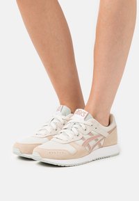 Lätta sneakers med en blandning av beige mocka och mesh, ljusrosa detaljer och en vit gummisula med rundad tådesign.