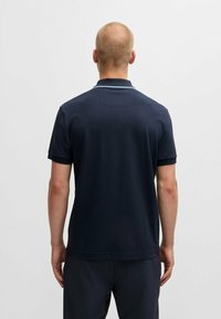 Polo shirt blu navy in cotone con colletto classico, maniche corte e strisce accentuate blu chiaro. Vista posteriore con orlo dritto.
