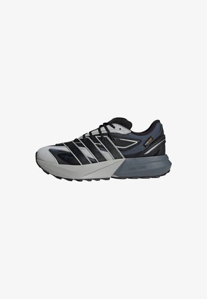Scarpe sportive con una tomaia nera e grigia, caratterizzate da un design testurizzato, un sistema di allacciatura prominente e una suola imbottita di un grigio chiaro.