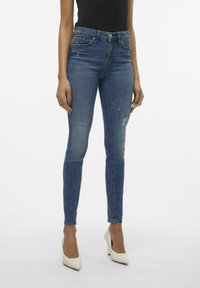 Lieknos mėlynos džinsos su išblukusiu audiniu ir šiek tiek pažeidimu. Pagaminti iš džinsinio audinio, pasižymintys vidutinio aukščio juosmeniu ir klasikiniais penkių kišenių dizainu.