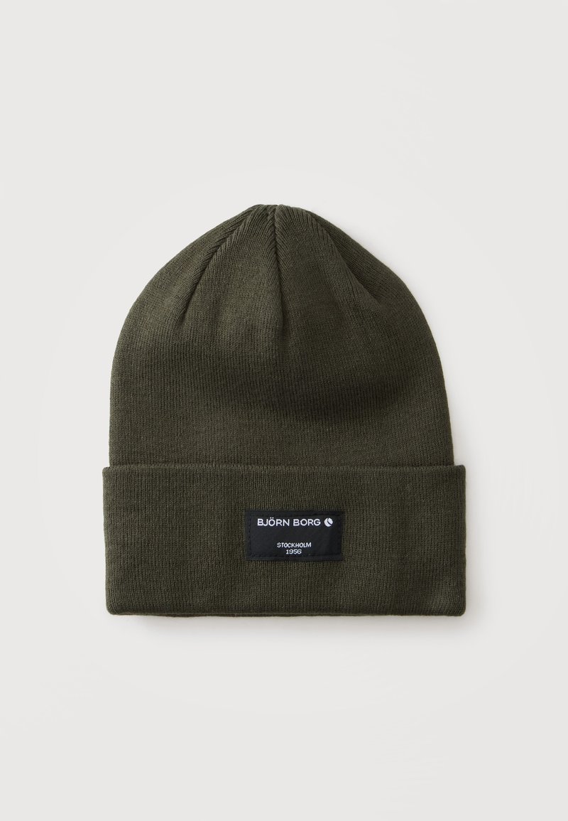 Bonnet tricoté vert foncé avec un revers plié comportant une étiquette noire indiquant "Björn Borg Stockholm 1956" sur un fond gris clair.