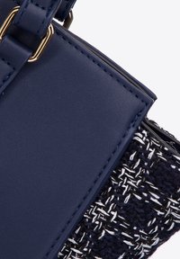 Navy blue leather handbag with woven textile section; features gold hardware and contrasting stitching, textured surface, and structured shape.