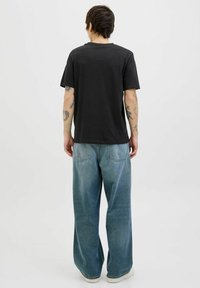 Zwarte katoenen t-shirt met korte mouwen, gecombineerd met loszittende lichtblauwe denim jeans. Heeft een casual, ontspannen silhouet.