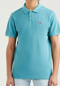 Turkos polo-tröja i mjuk bomull, med en tre-knapp-krok, korta ärmar och en liten röd Levi's-logotyp på vänster bröst.