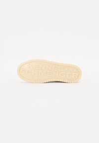 Semelle de chaussure en caoutchouc beige avec du texte en relief "KENNEL SCHMENGER" et des accents en forme d'étoile, dotée d'un motif texturé pour une adhérence optimale.