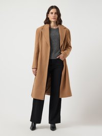 Camel wool coat with large lapels, worn over a gray sweater and black wide-leg pants. Black pointed-toe boots complete the look.