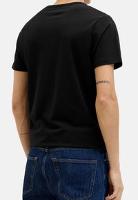 Zwarte short-sleeve t-shirt met een ronde hals, gemaakt van glad katoen, gedragen met blauwe spijkerbroek, met een zichtbare tatoeage op de arm.
