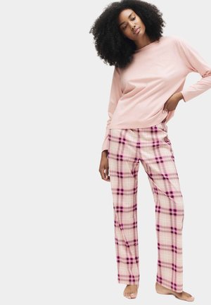 Een lichtroze longsleeve top en een geruit broek in lichtroze met paarse en donkerroze lijnen, met een ontspannen pasvorm en zachte textuur.