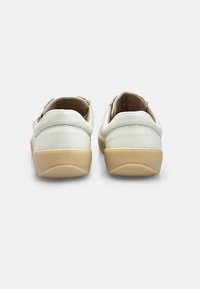 Scarpe in pelle bianca con forma arrotondata, caratterizzate da una texture liscia e una suola in gomma beige. Il design presenta accenti minimi sul tallone.