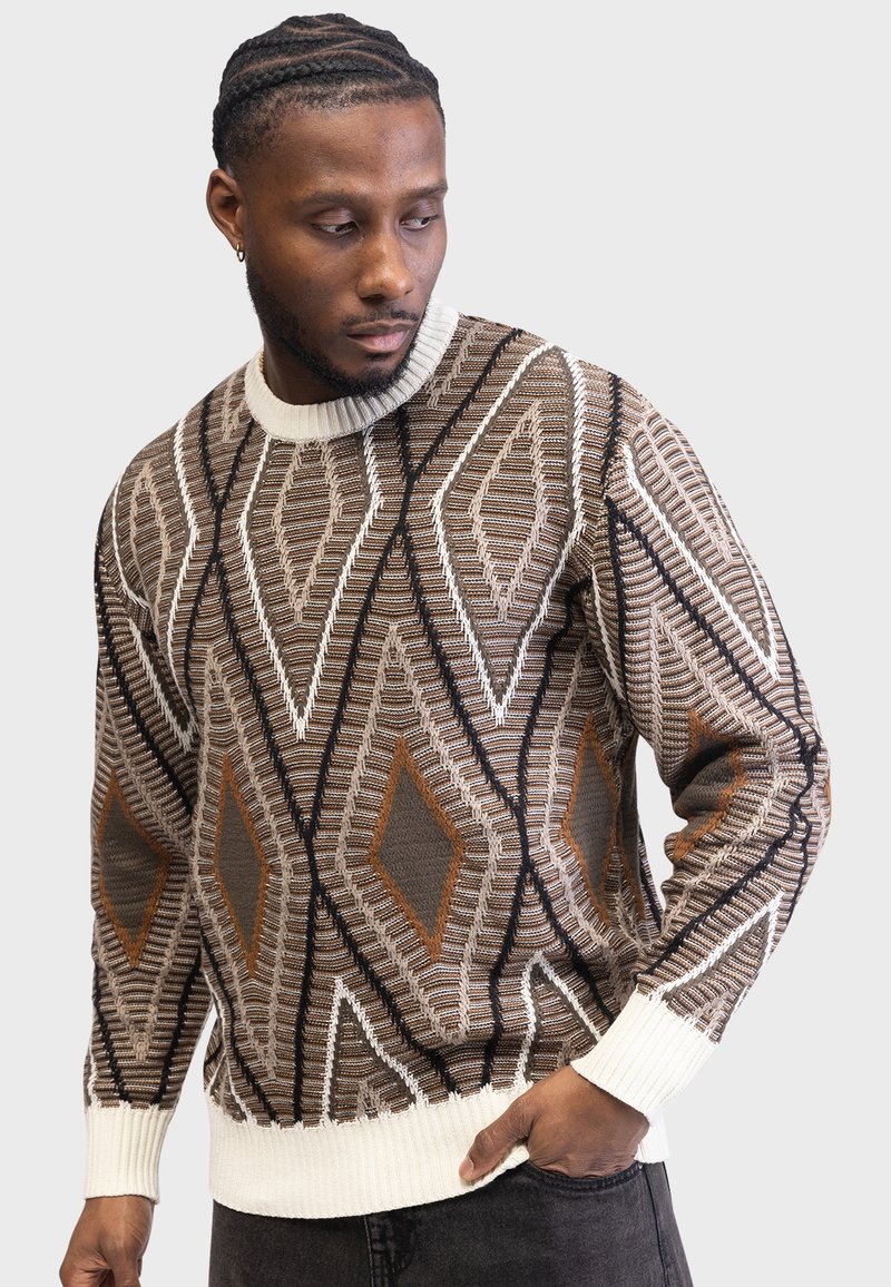 Brown patterned sweater with diamond shapes in beige, white, and rust. Ribbed white cuffs and hem. Made from textured knit fabric.