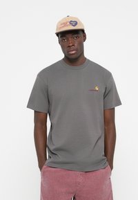 Gray cotton t-shirt with a crew neck and short sleeves, featuring a small orange and red logo on the left chest.