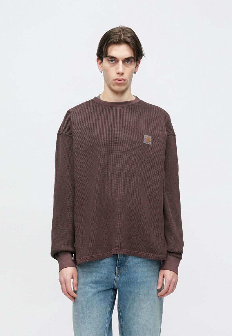 Brun tekstureret langærmet sweatshirt med rund hals og ribbet kant ved ærmerne, med et lille orange logo på brystet.